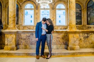 A romantic moment shared in a grand marble hall with classical architecture.