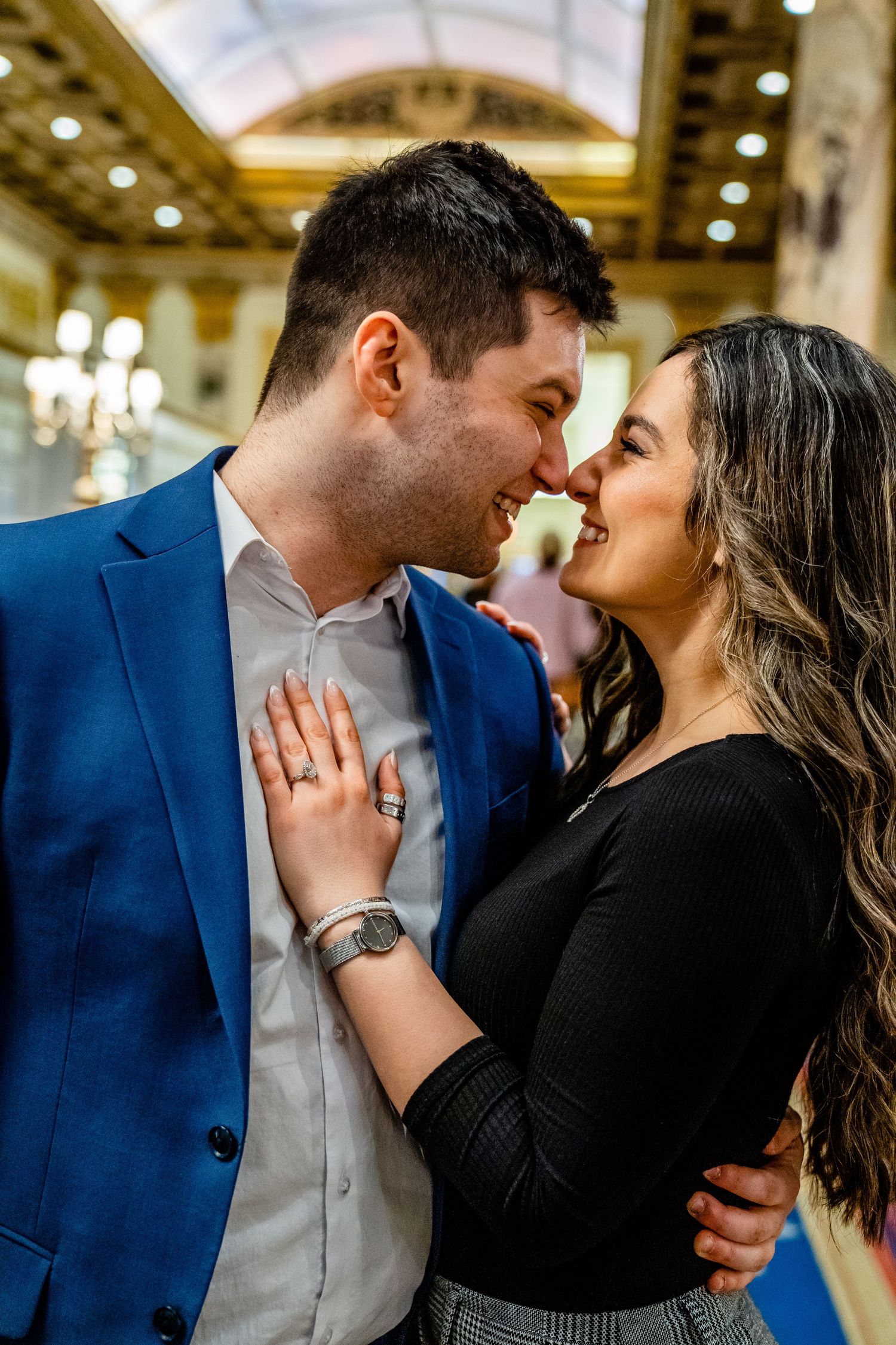 A close intimate moment shared in an elegant hallway with ornate ceiling details.