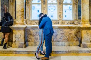 A tender embrace in an elegant marble hallway with classical architecture.