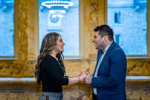 A tender interaction between two people in an elegant room with golden walls and chandeliers.
