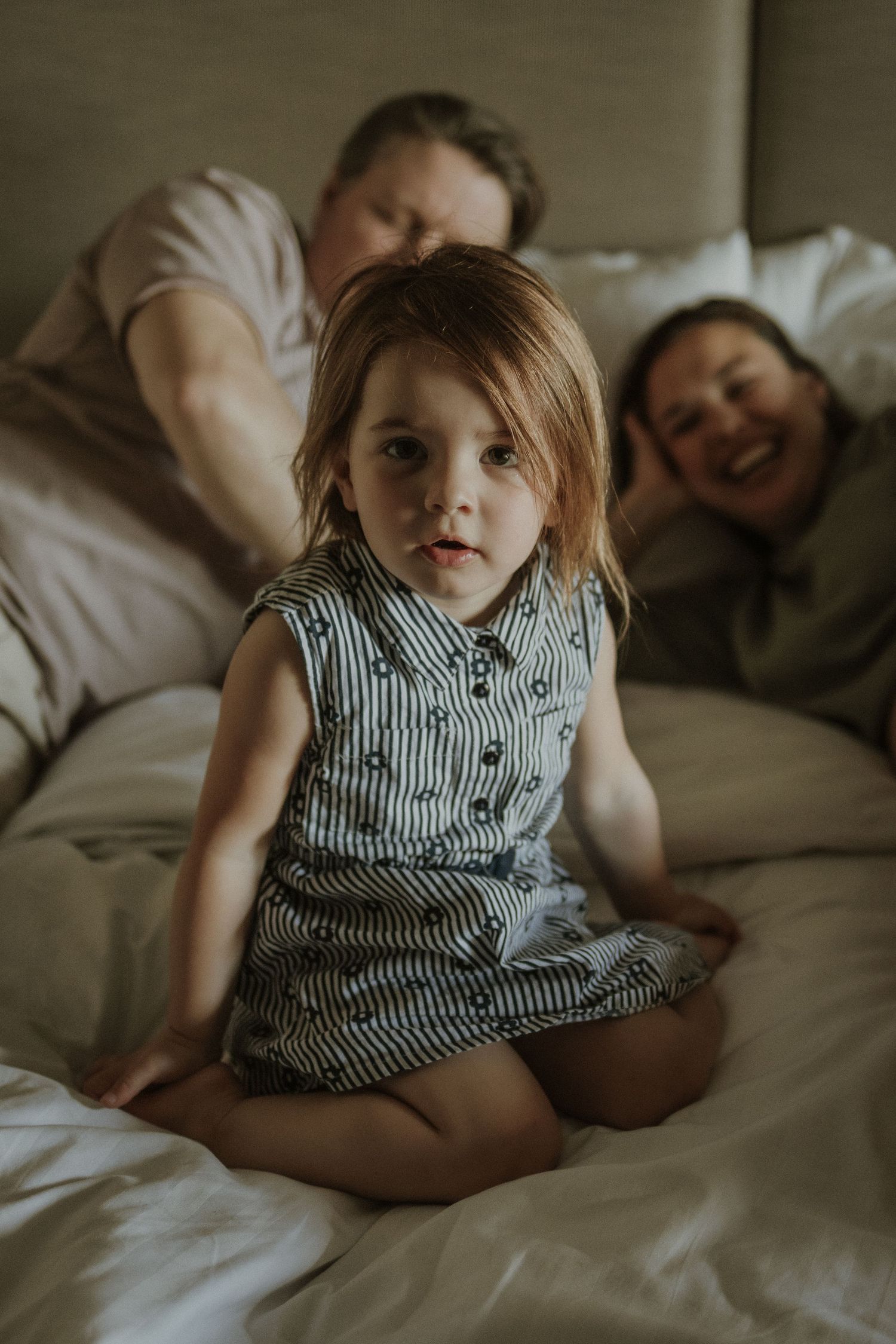little girl sitting on the bed at home with her mum and dad