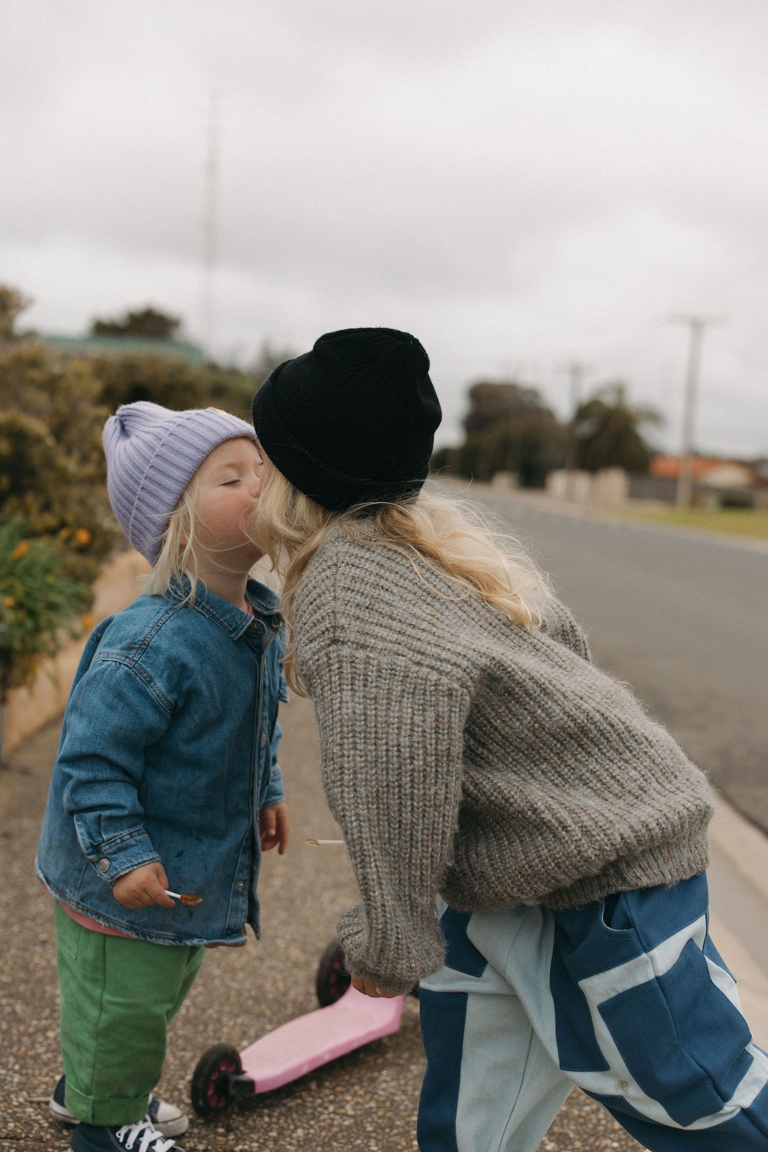 Two people in winter clothes sharing a playful moment outdoors on a cloudy day.