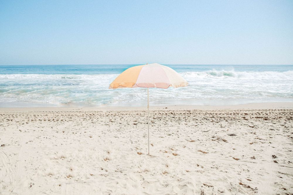 A minimal photograph of an pastel umbrella on a California beach