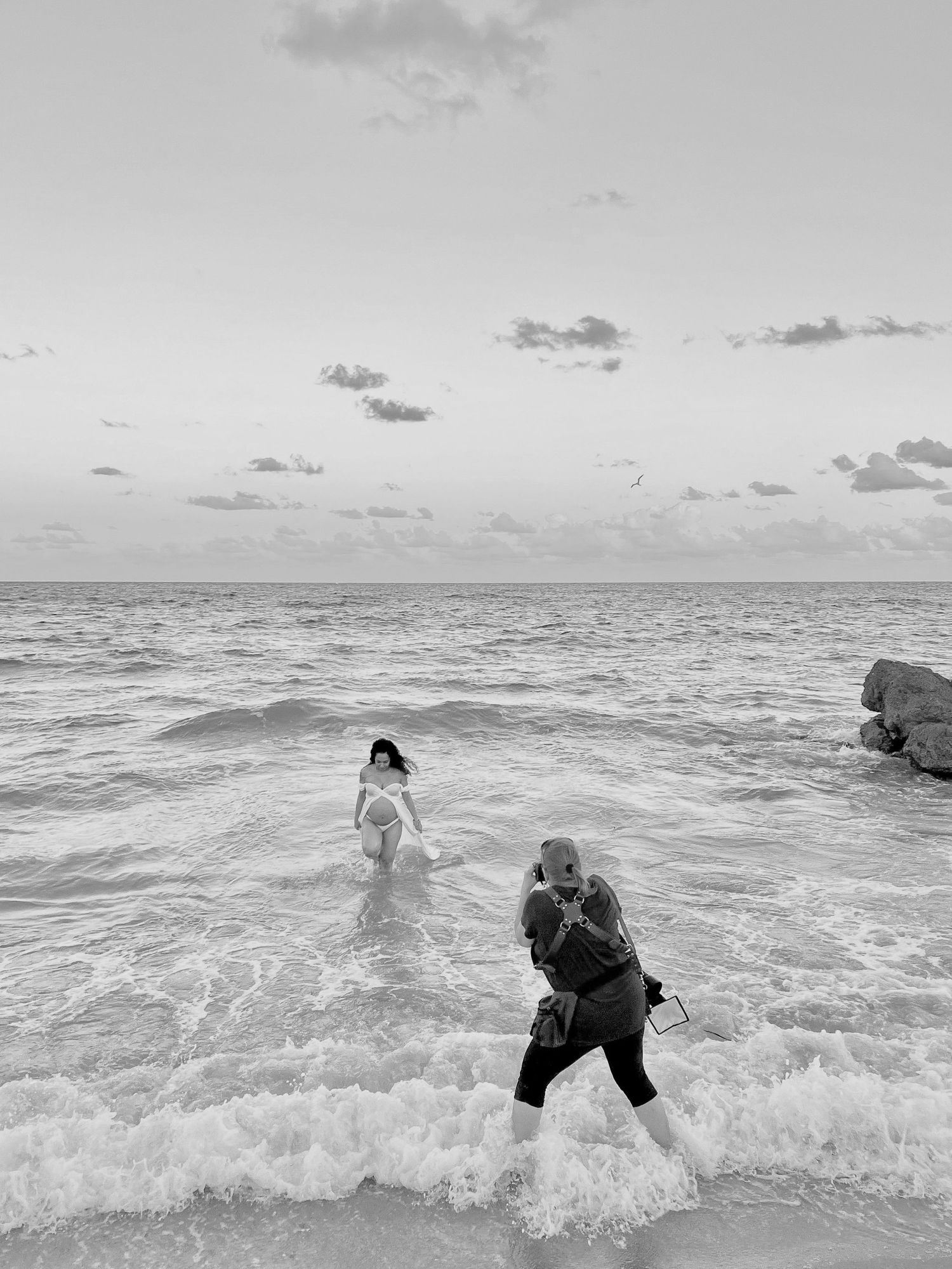 Photo of photographer, INGER Kirkeleit at a beach session photographing a pregnant woman coming out of the water.