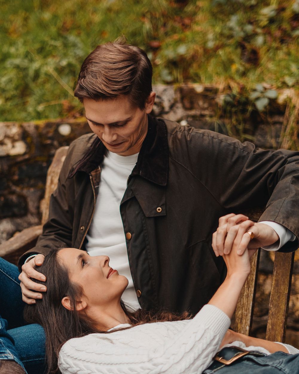 A couple relaxes on a wooden bench in an intimate outdoor setting.
