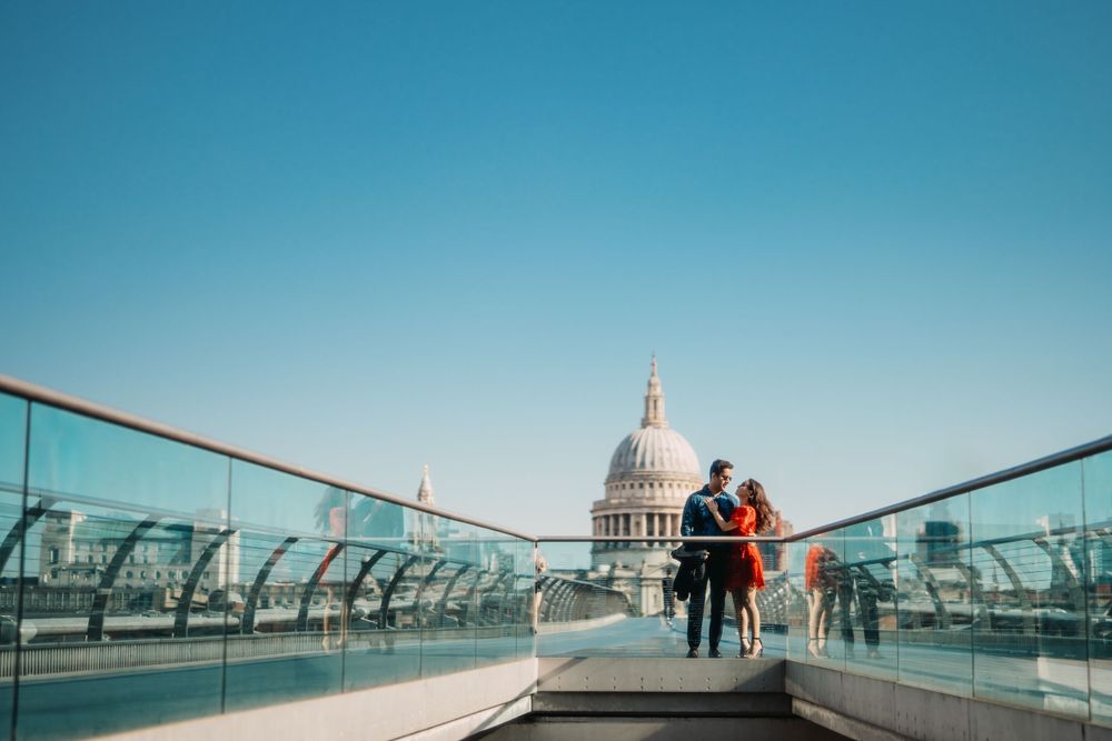 creative photo of a couple on Millennium Bridge with St Pauls cathedral in the background in London
