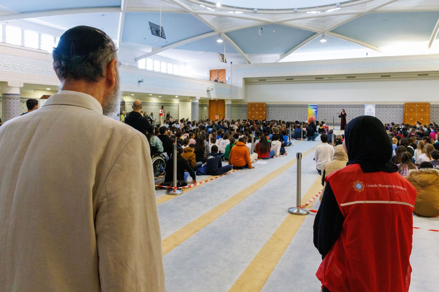 Interior of an airport terminal with passengers waiting in a queuing area.