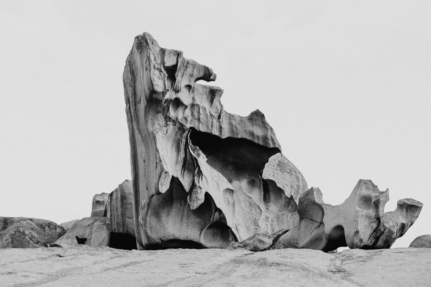 Dramatic black and white landscape of jagged rock formations against light background.