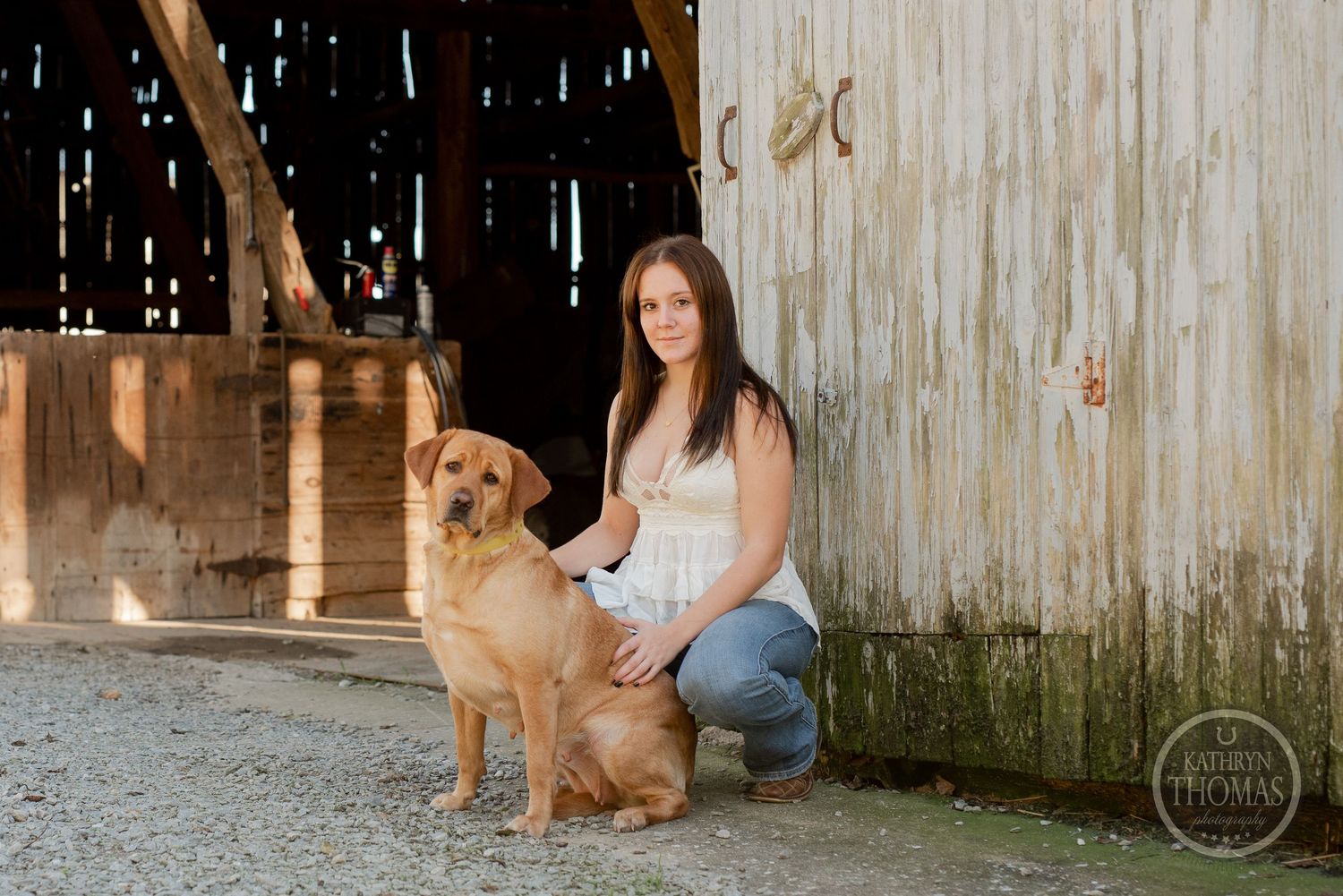 Sitting with golden retriever outside rustic barn on sunny afternoon.