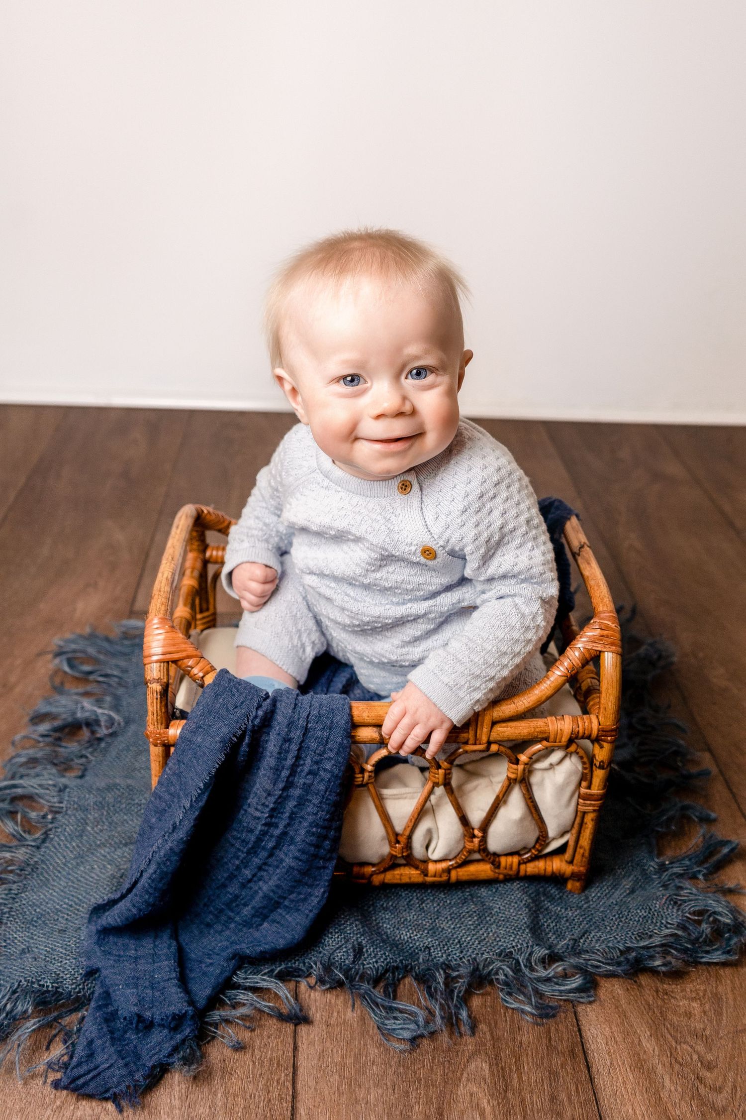 baby boy at sitter session in basket with blue blanket, smiling portrait with client of heather katie photography.