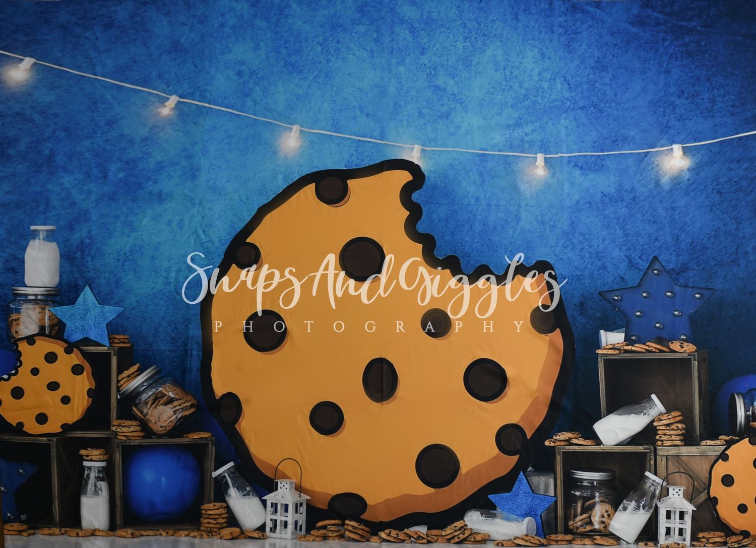 Giant cookie prop with string lights against blue backdrop for photography setup.