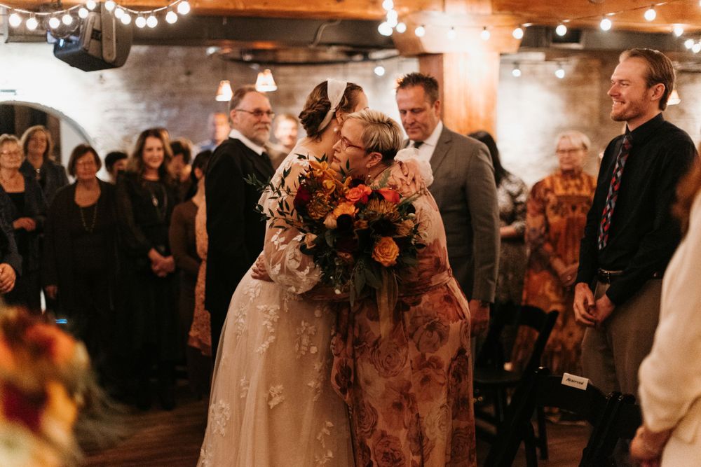Bride and mother share an emotional kiss at the wedding ceremony altar.