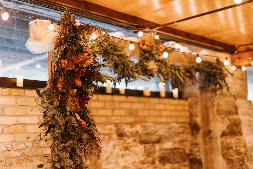 Lush greenery garland with warm string lights decorating a rustic brick wedding venue.