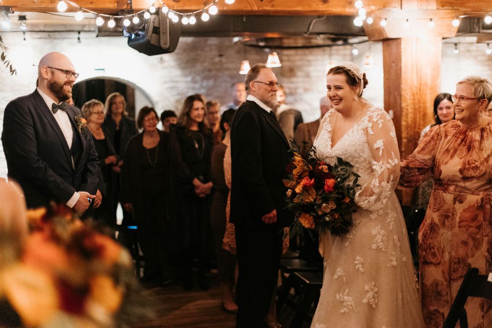 Bride and groom share a joyful moment at the altar of a rustic wedding venue.