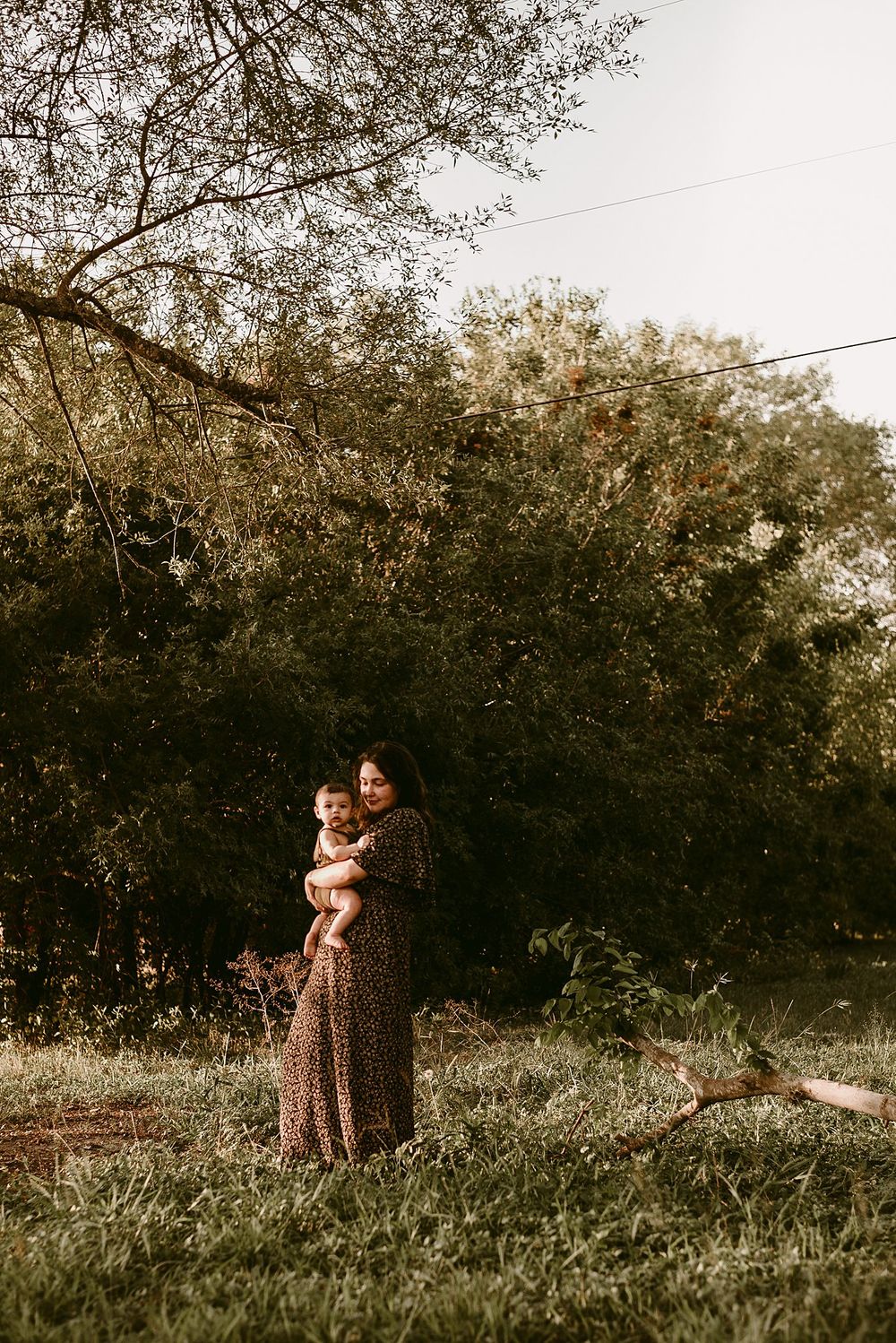 A tender family moment captured in warm sepia tones against a natural outdoor backdrop.