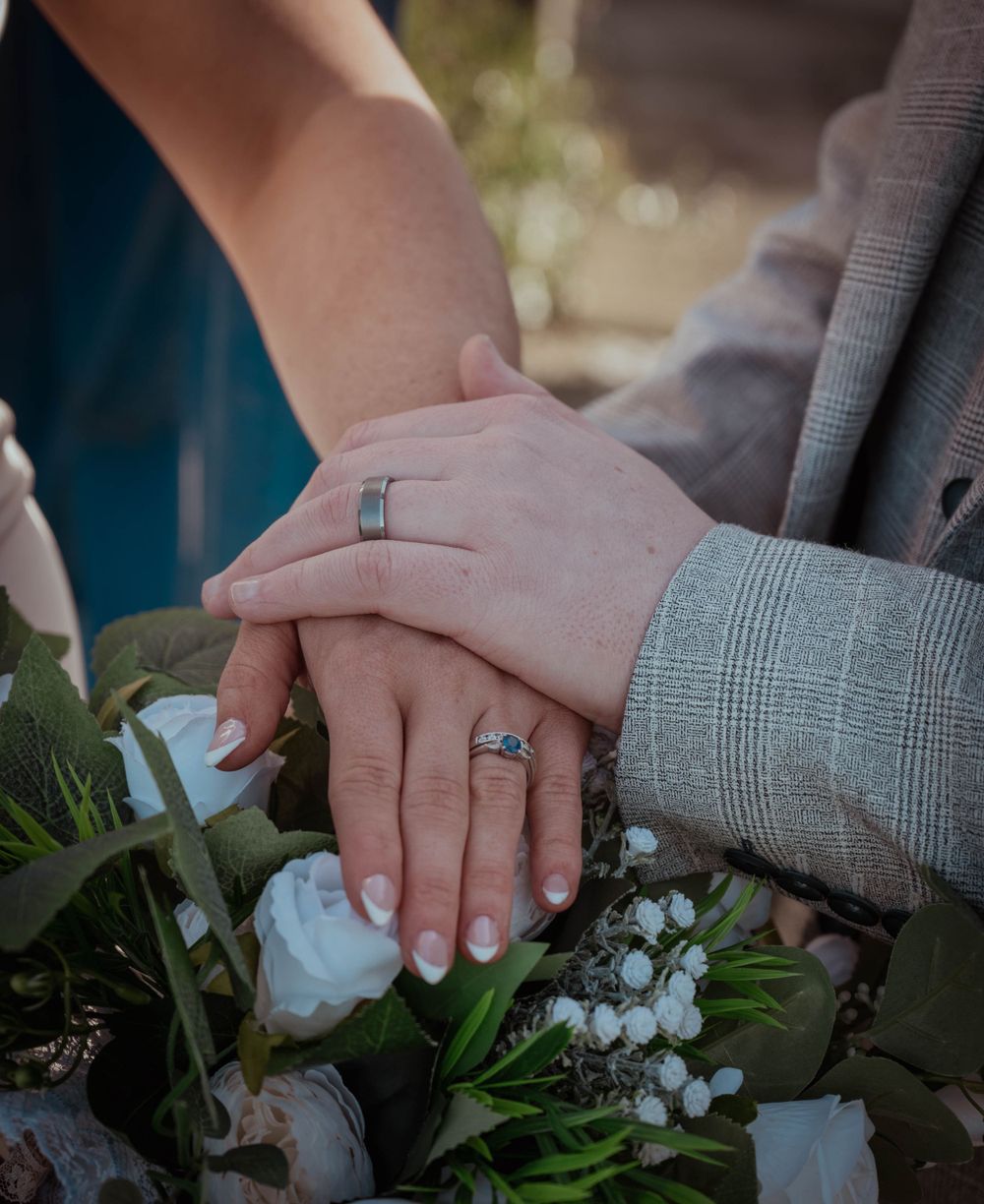 Bride and groom holding hands showing off their new wedding rings
