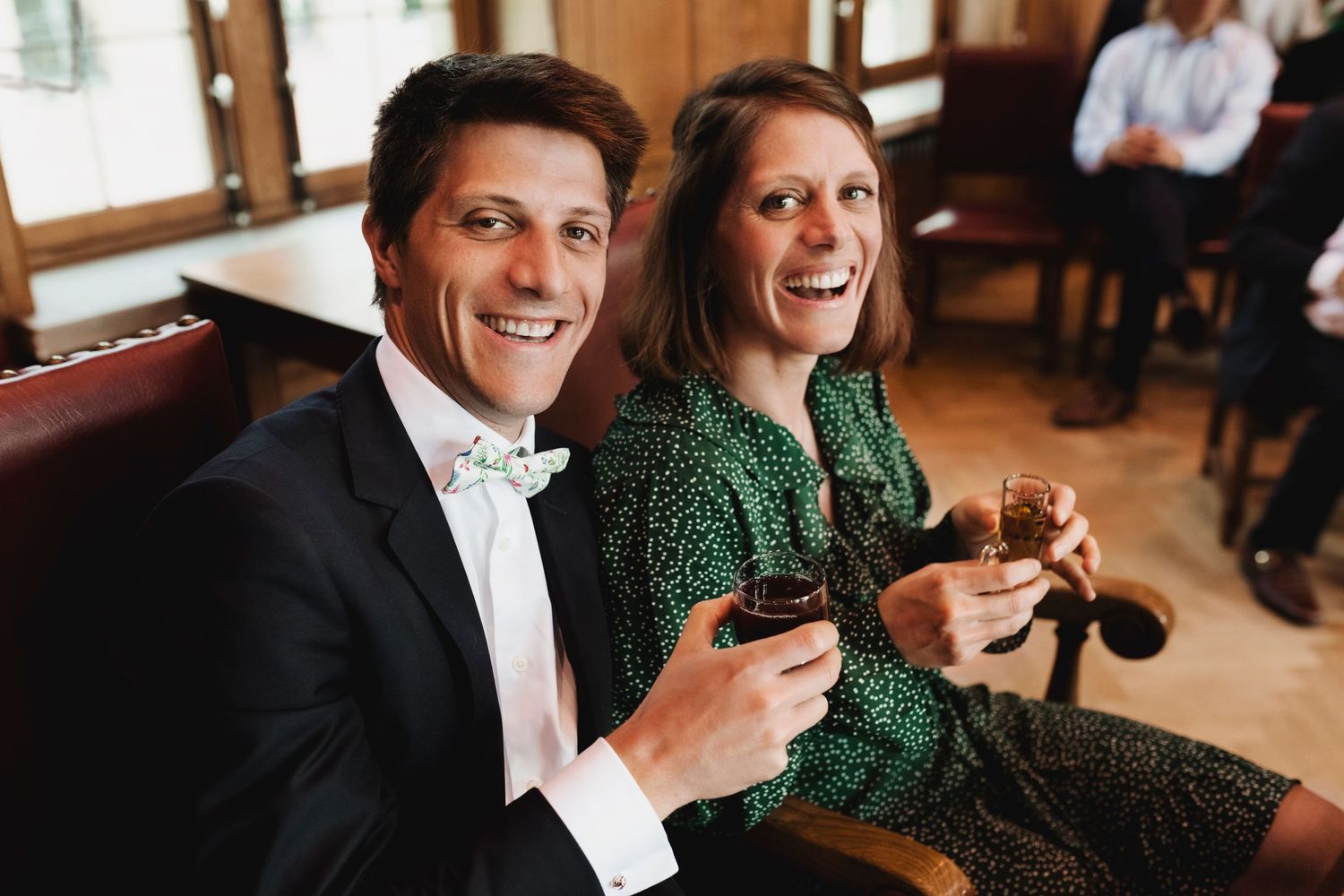 A well-dressed couple enjoys drinks together during a celebration.
