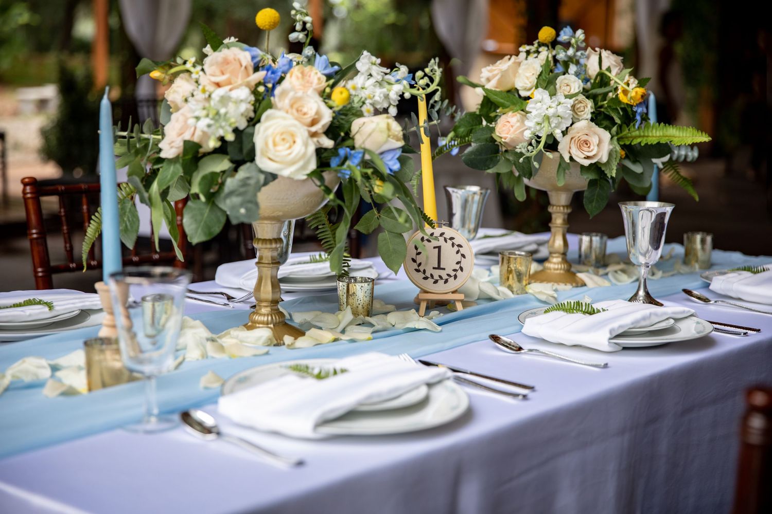 Elegant wedding reception table settings with white floral centerpieces and gold accents.