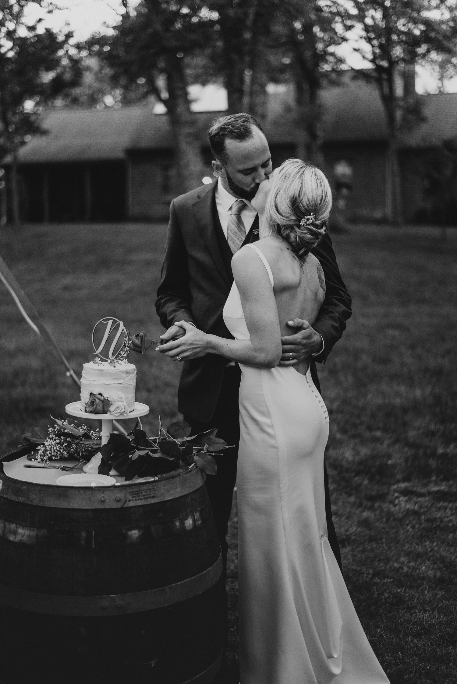 A couple shares an intimate moment while cutting their wedding cake at an outdoor reception.