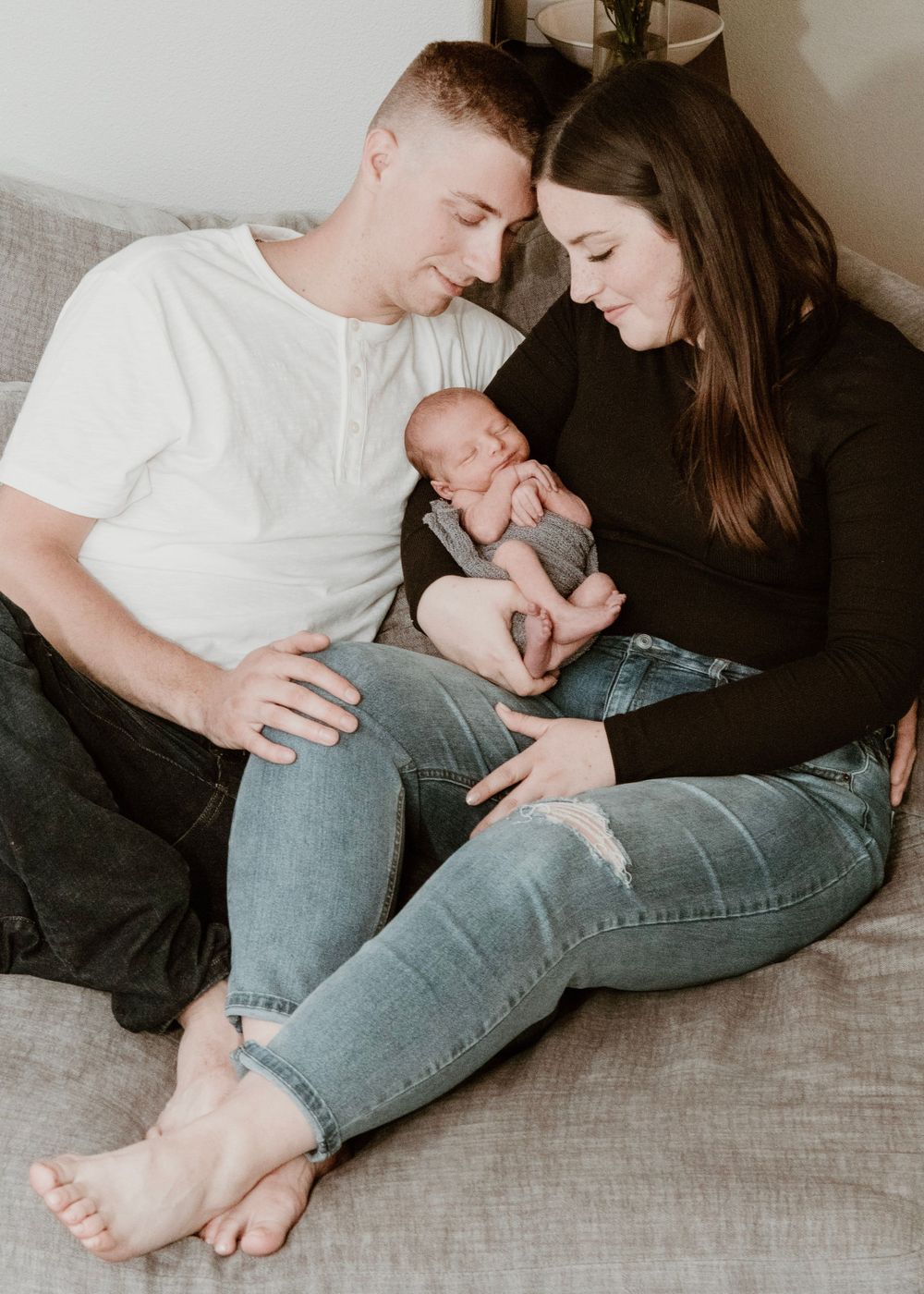 Family sharing an intimate moment together on a grey couch in casual attire.