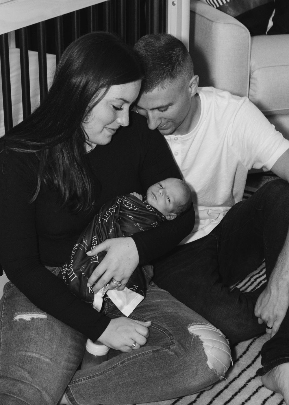 Family sharing intimate moment together near nursery furniture in black and white.