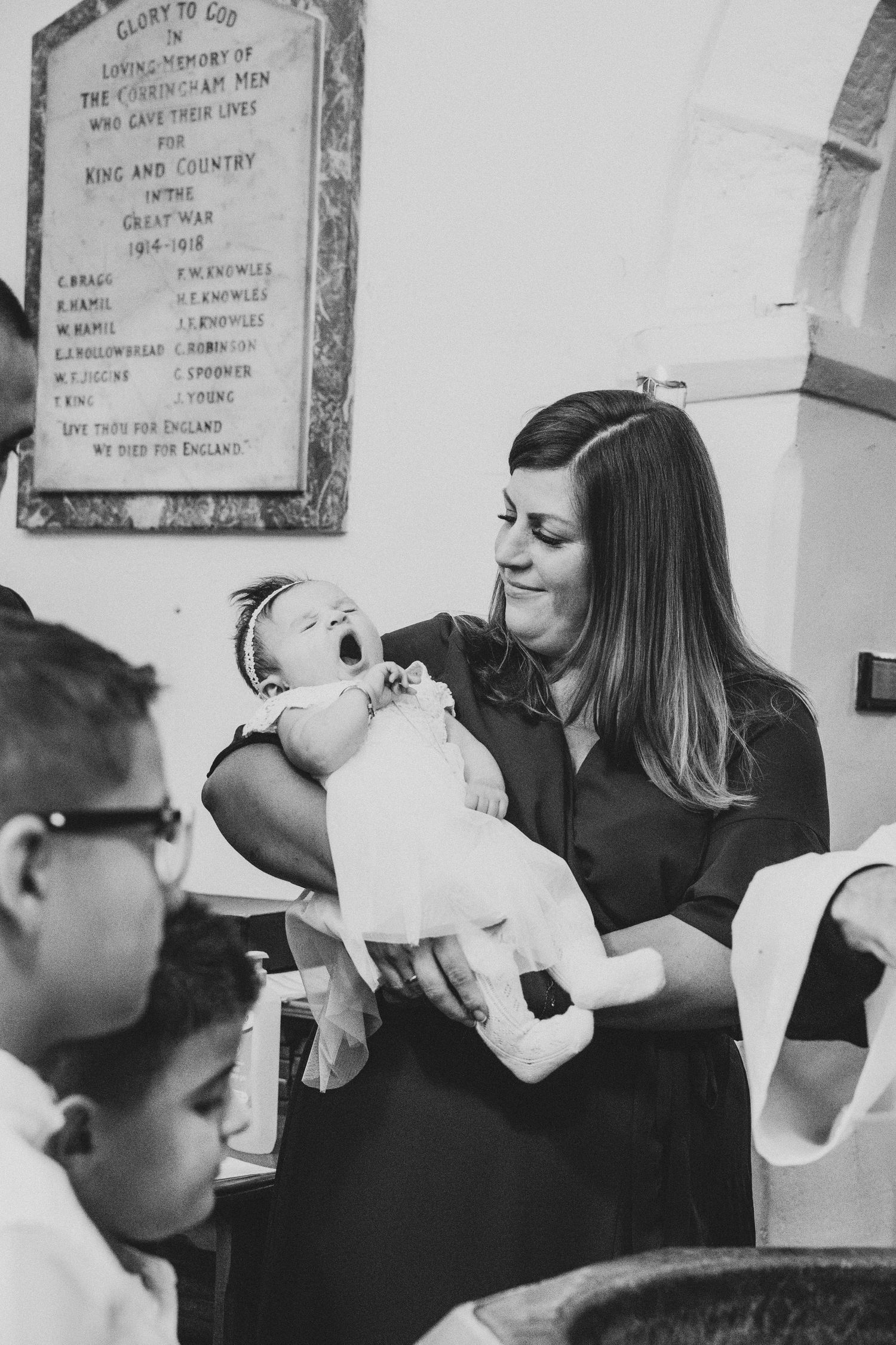 Black and white photo of a baptism ceremony showing participants gathered around a church font.