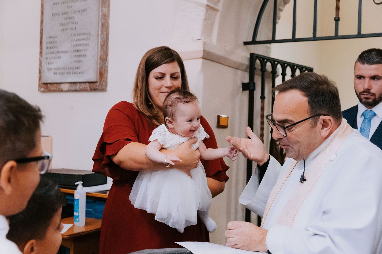 A religious ceremony takes place around a baptismal font in a church interior.