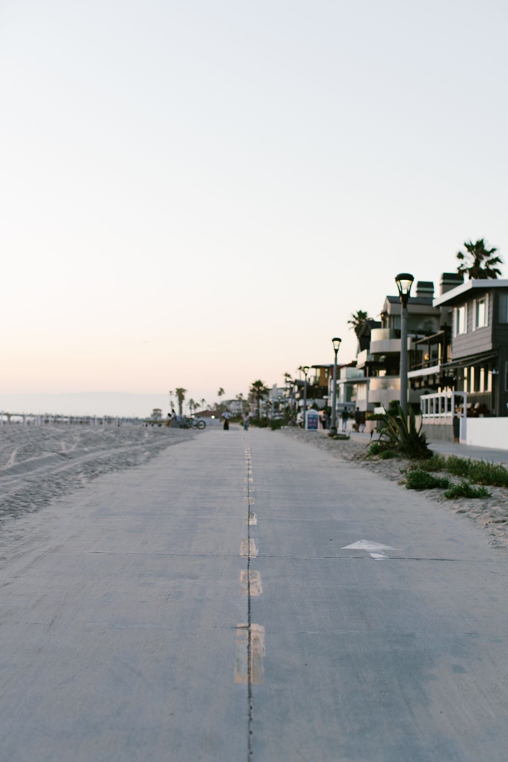 A beachfront boardwalk lined with modern homes at dusk.