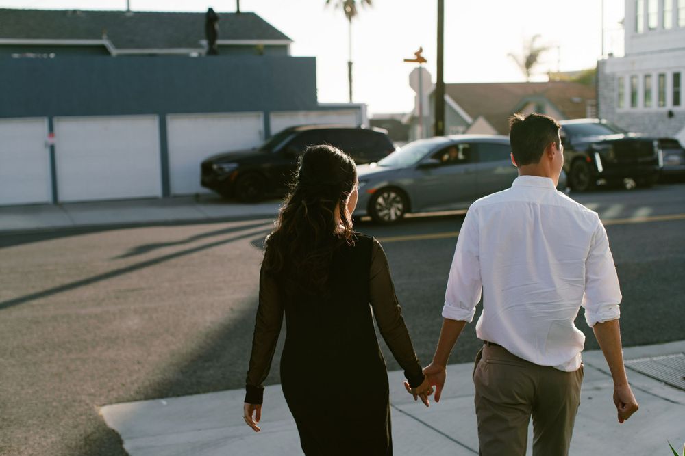 Couple holding hands while walking together on a quiet street at sunset.