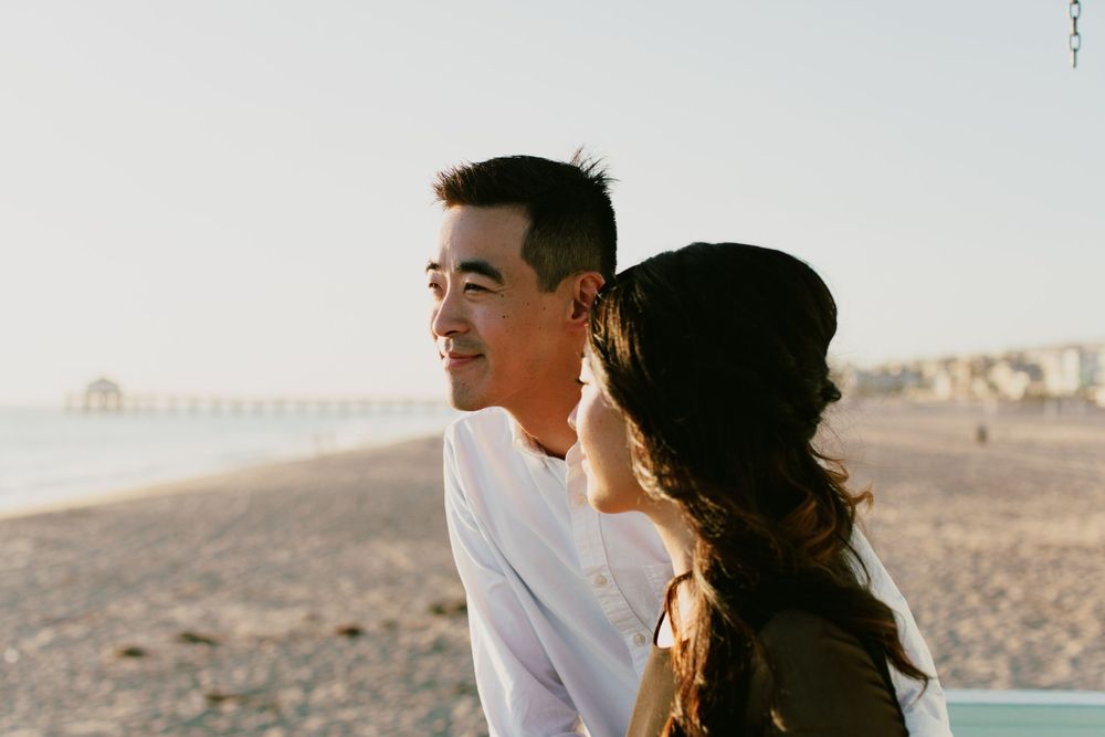 A couple shares an intimate moment on the beach with the ocean in the background.