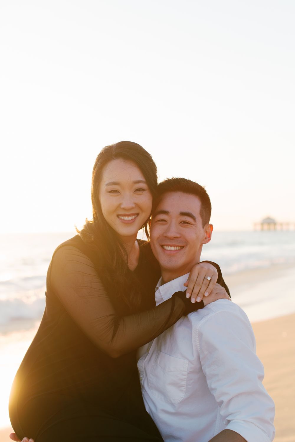 A joyful couple embraces on the beach during golden hour.