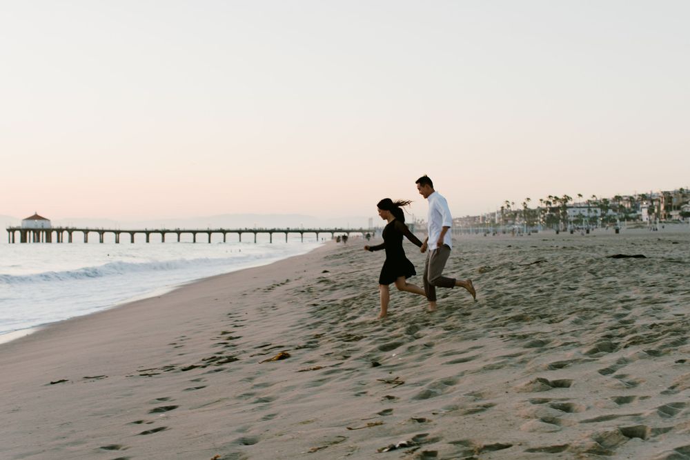 Silhouettes of a couple dancing on the beach with a pier in the distance.