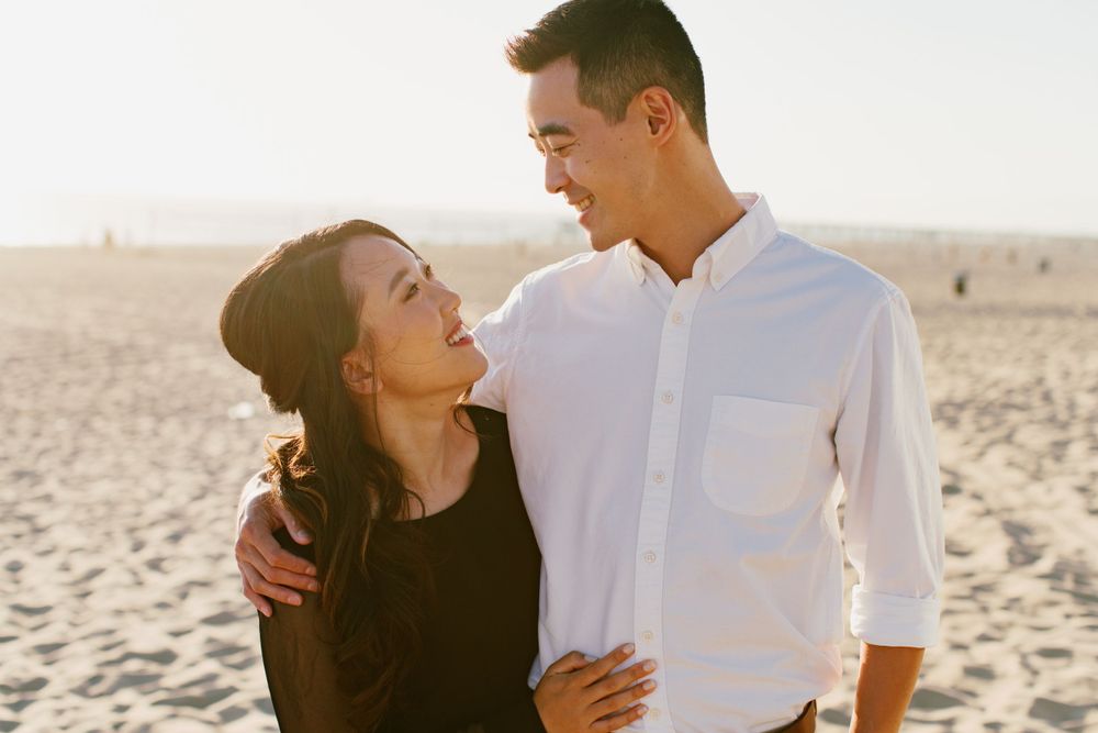 Romantic couple sharing a tender moment on the beach in warm sunlight.