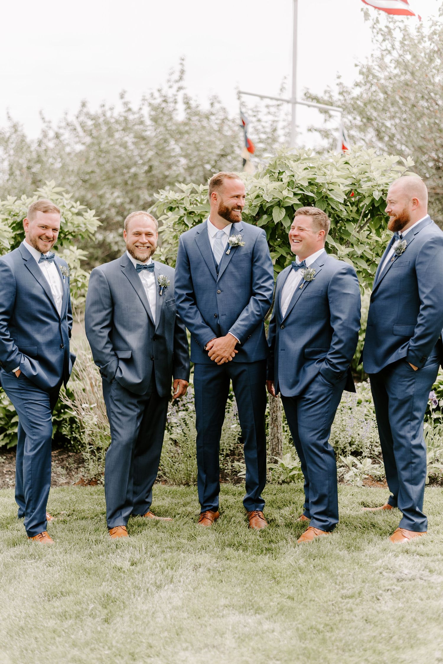Groomsmen in navy suits share a lighthearted moment outdoors.