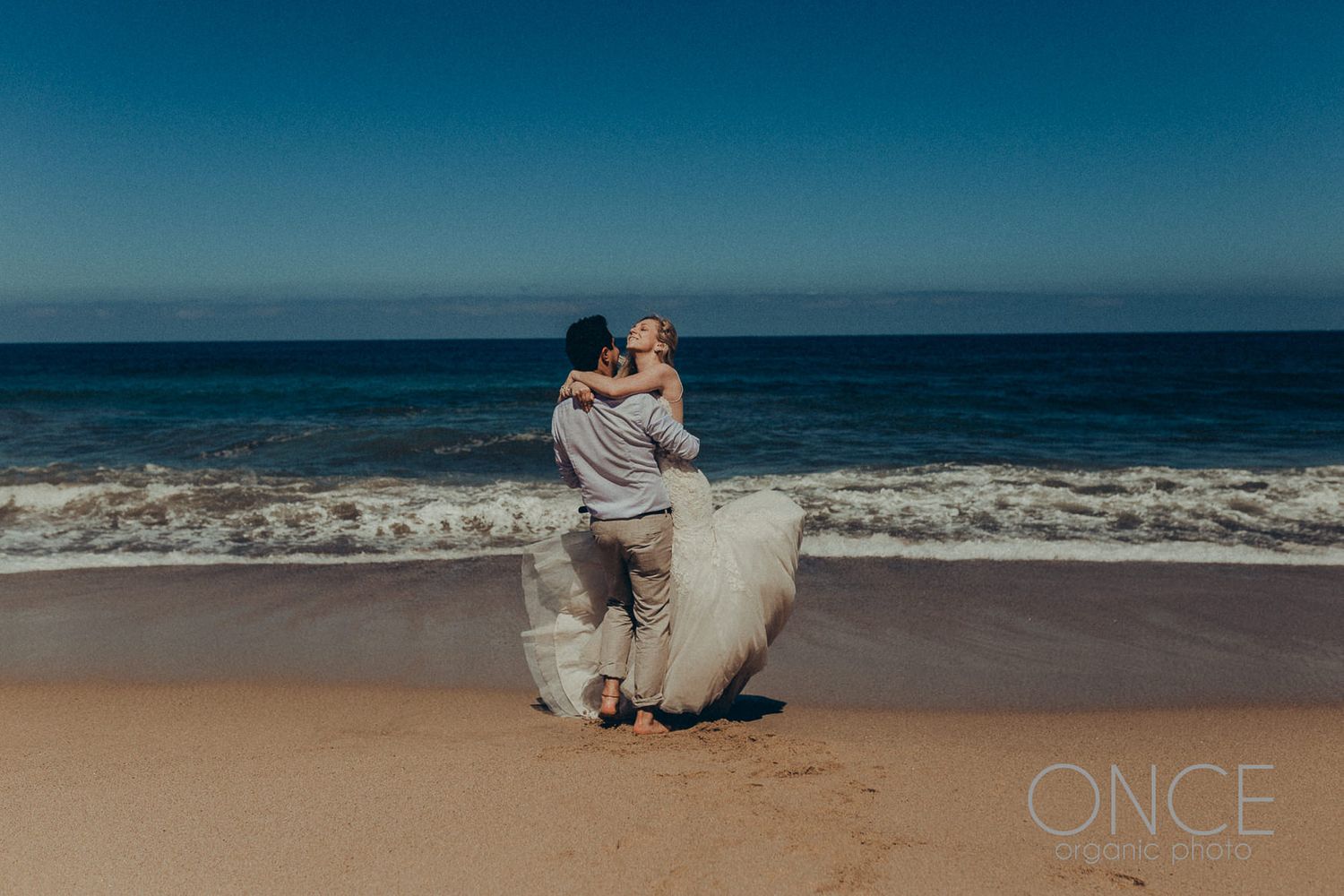 A romantic beach embrace with waves crashing in the background.