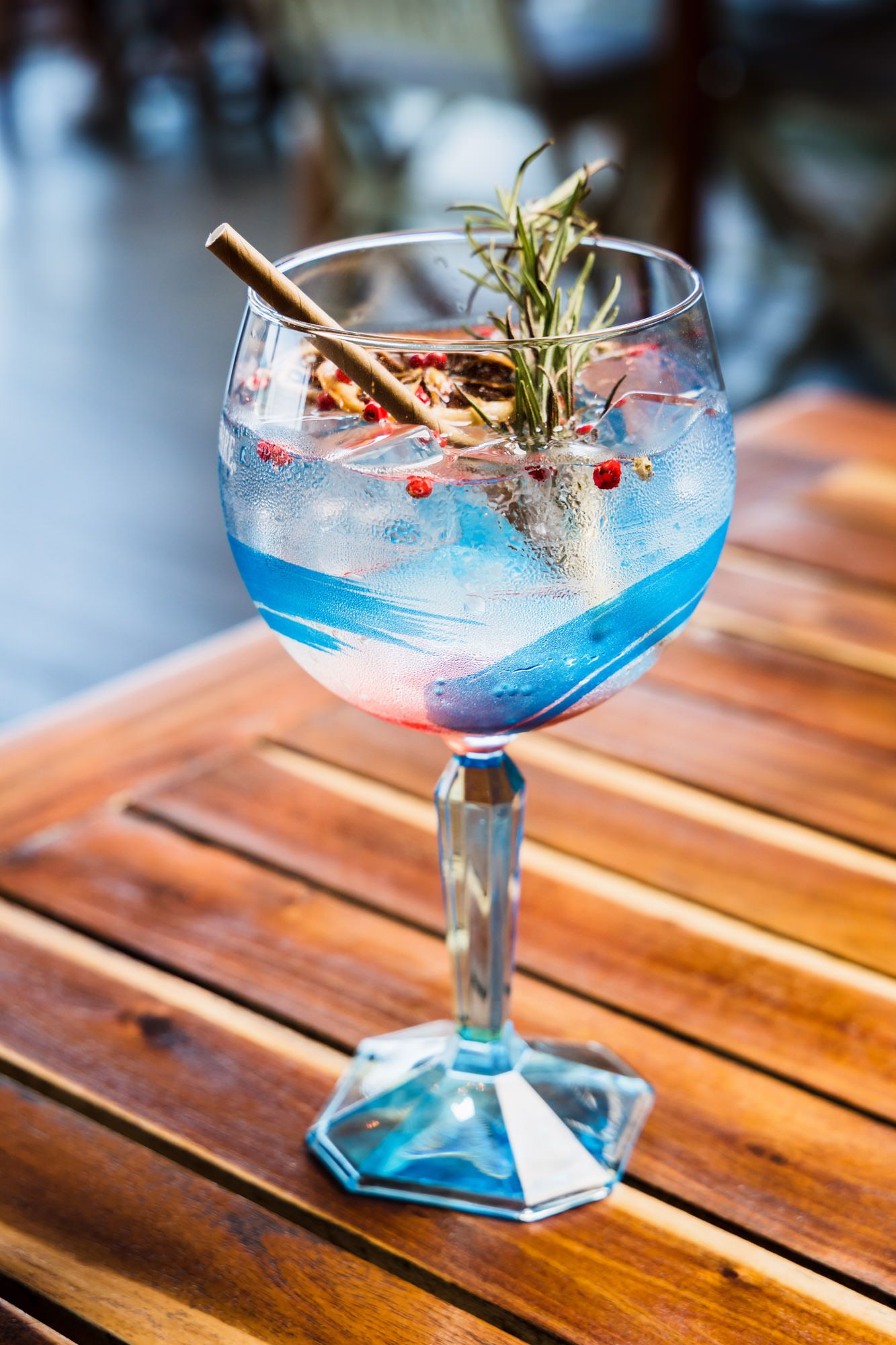 Vibrant blue cocktails garnished with herbs and berries served in crystal coupe glasses.
