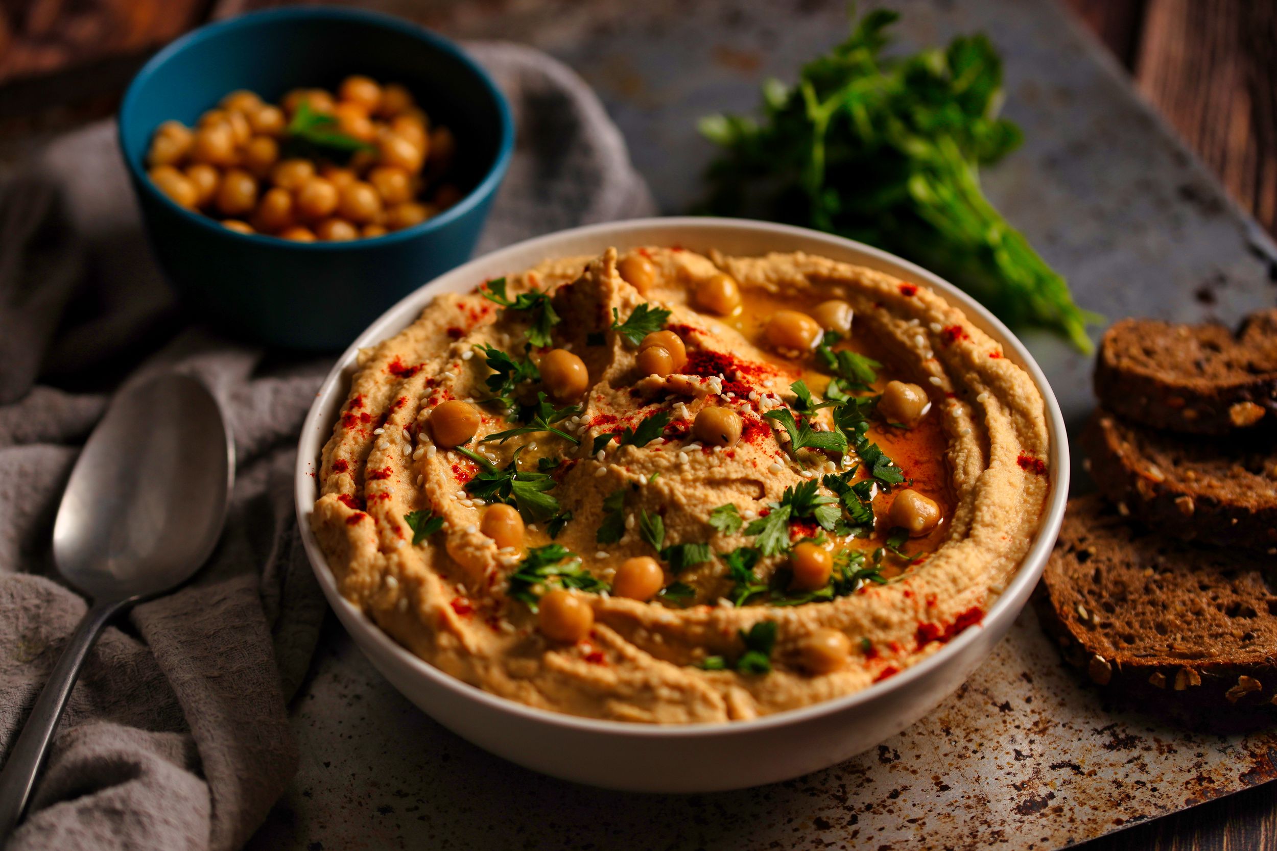 Bowls of creamy hummus garnished with herbs and spices.