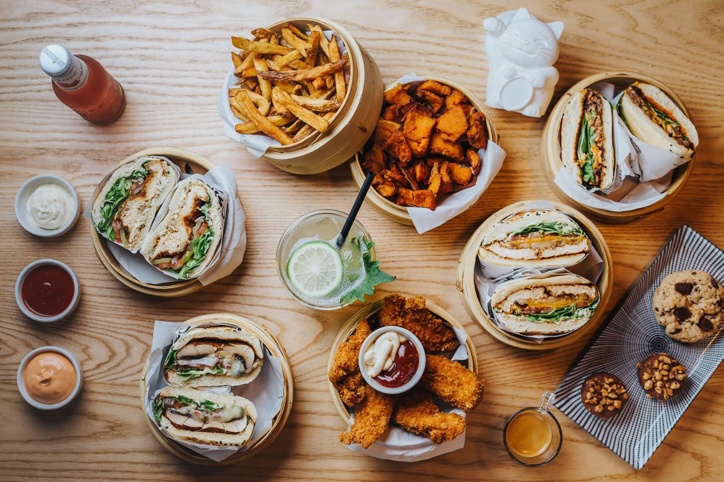 Overhead view of a casual restaurant table spread with sandwiches, chips, and various sides.
