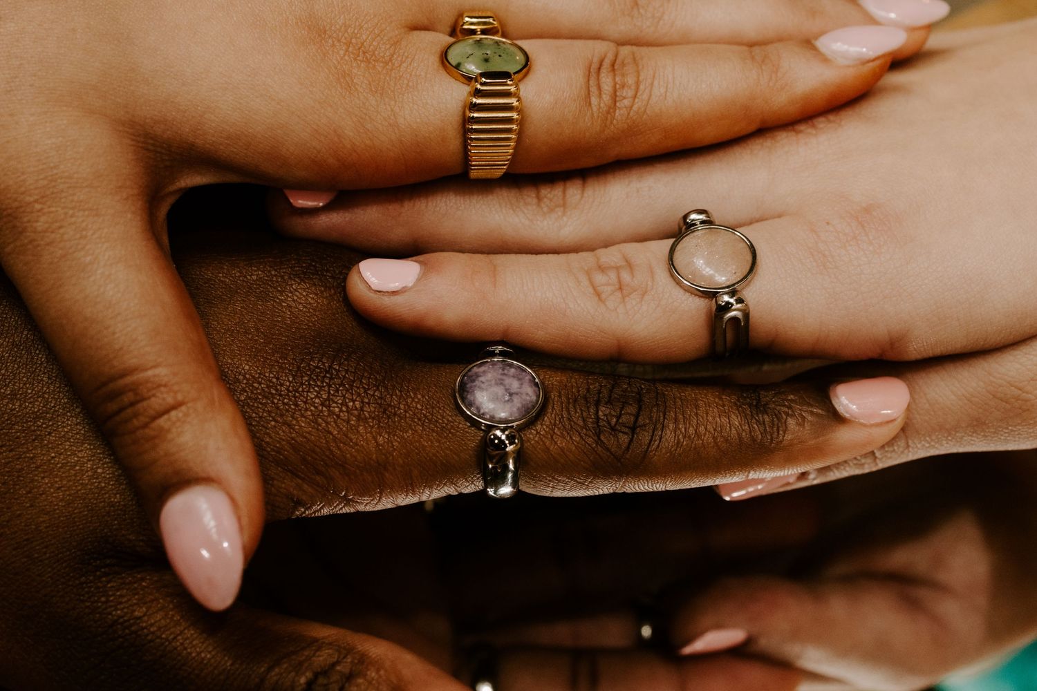 Close-up shot of hands wearing vintage style rings on brown leather surface.