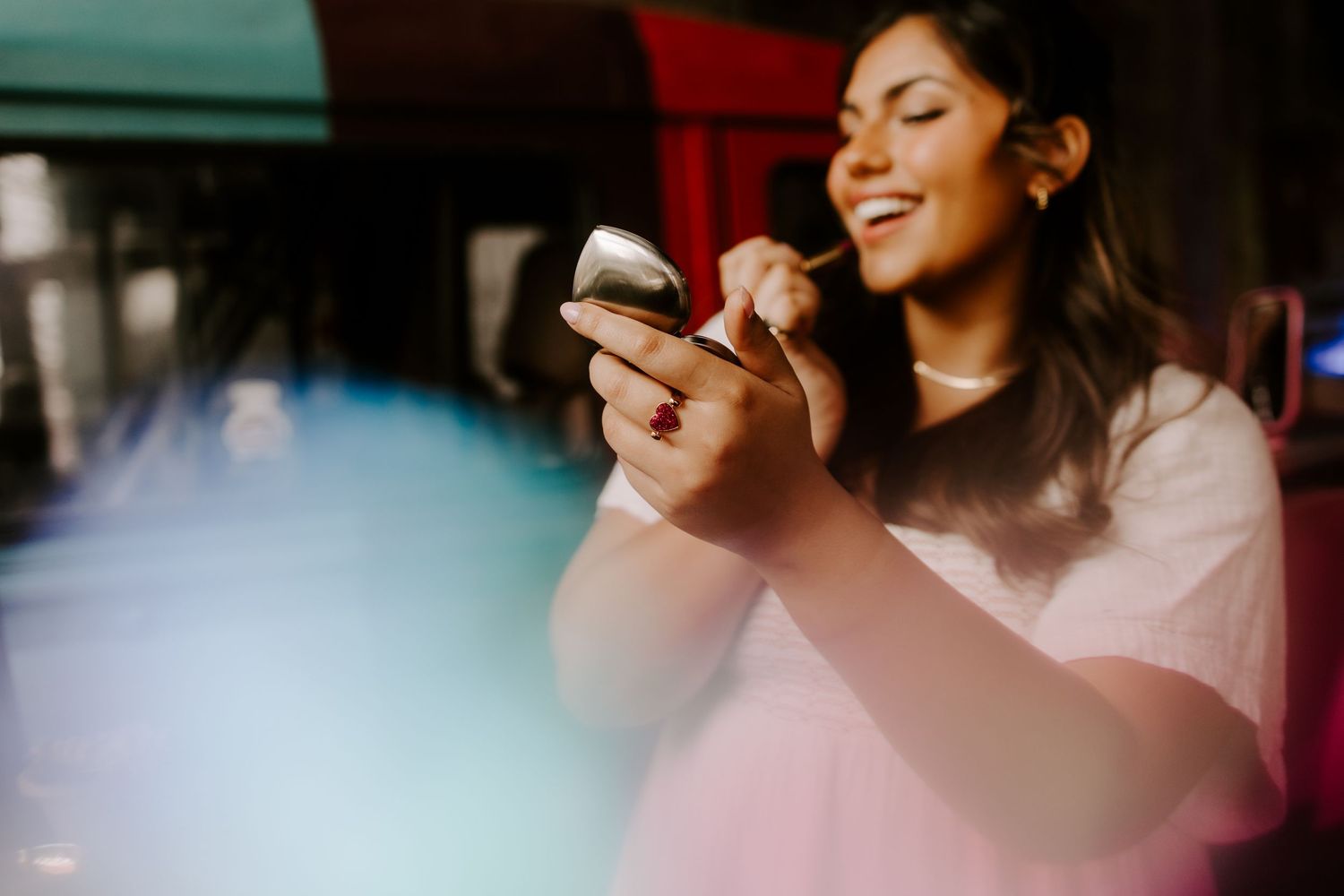 Woman smiling while looking at mobile phone in warm lighting.