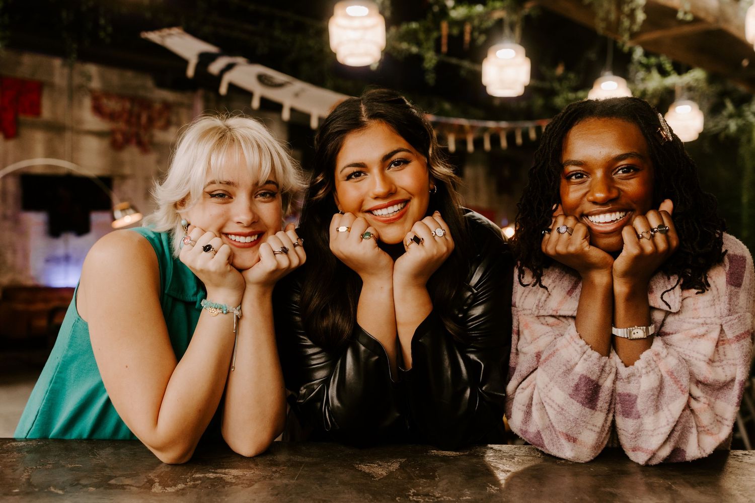 Friends posing together at bar with festive string lights and decorations.