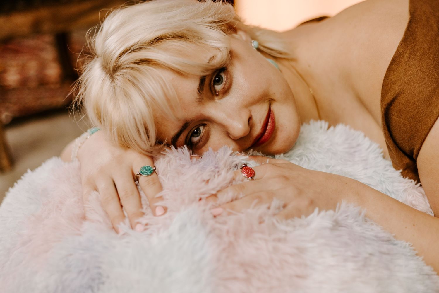 Artistic portrait with white fluffy pillow and turquoise jewelry.