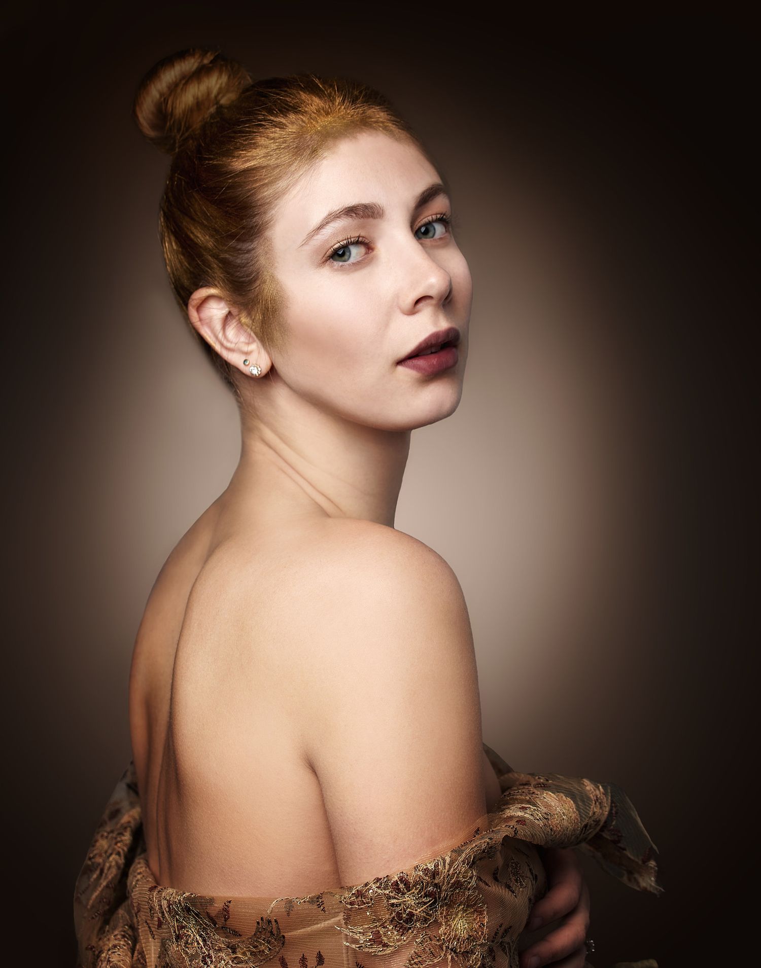 Classic glamour portrait with bare shoulders adorned by lace fabric against a dark background.