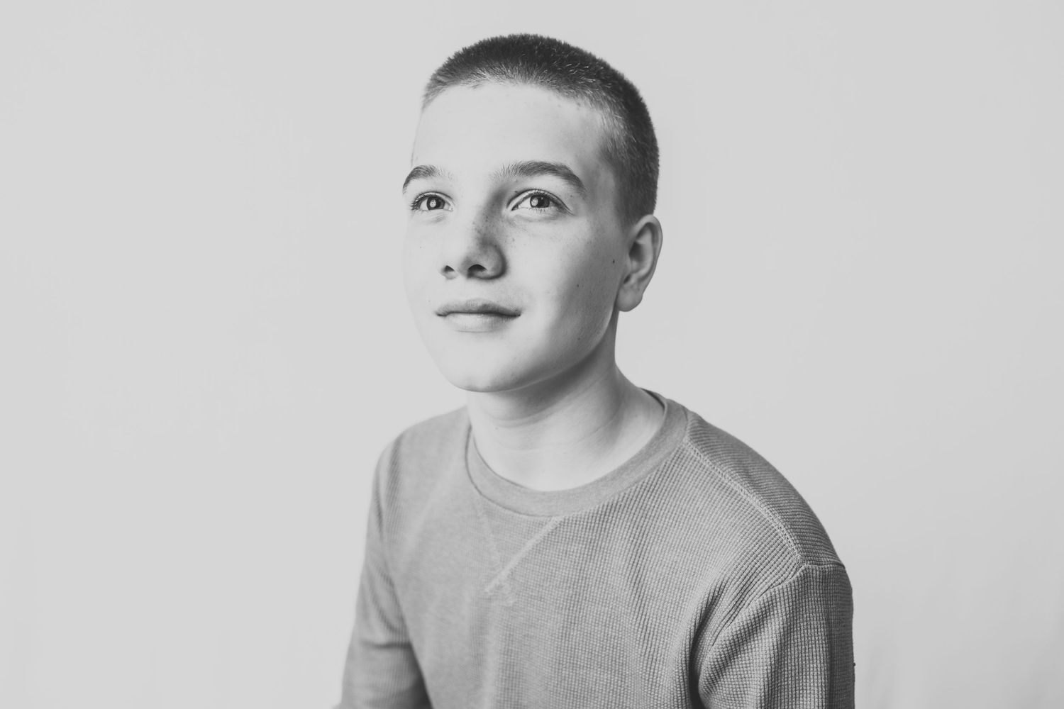Black and white portrait in light sweater with contemplative gaze.