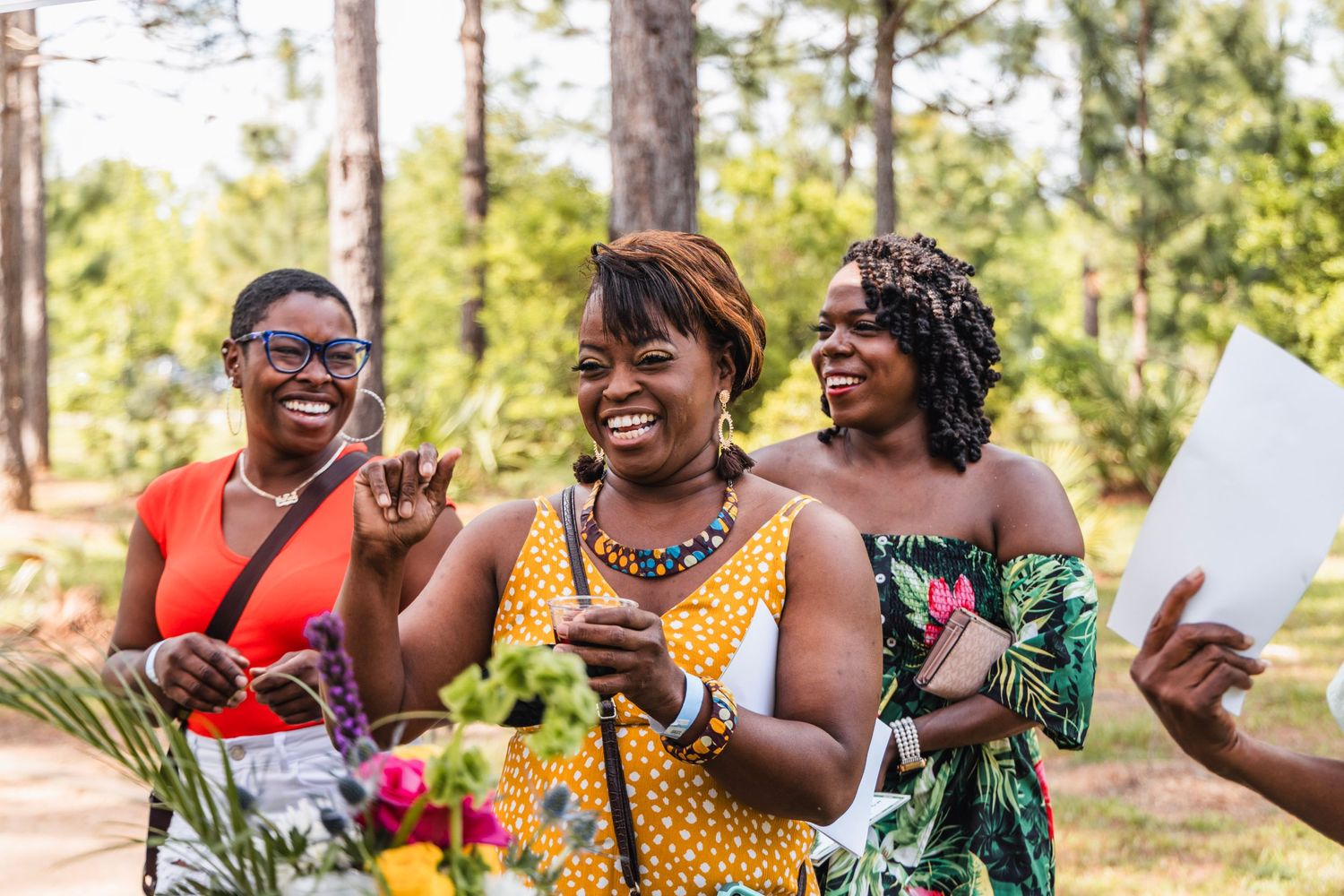 Group of friends laughing together outdoors in bright colorful clothing.