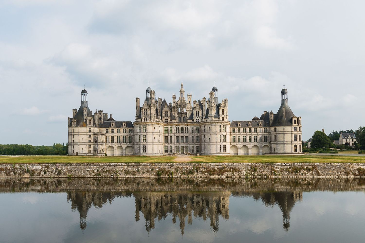 The Chateau de Chambord castle reflects perfectly in still waters on a cloudy day in France's Loire Valley.