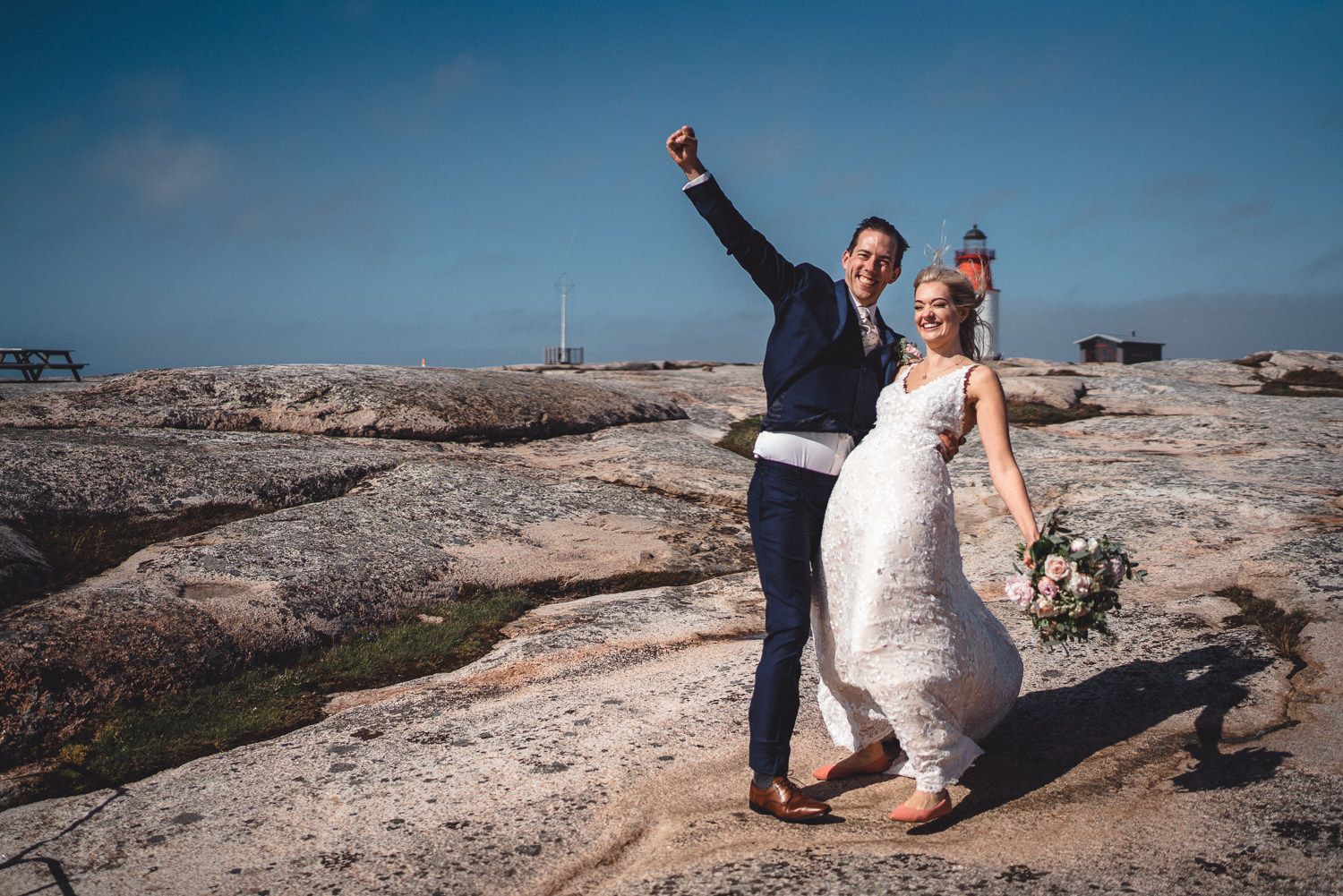 Brudpar firar framför Hållö Fyr strax utanför Smögen i Bohuslän en sommardag de är glada och himlen är blå