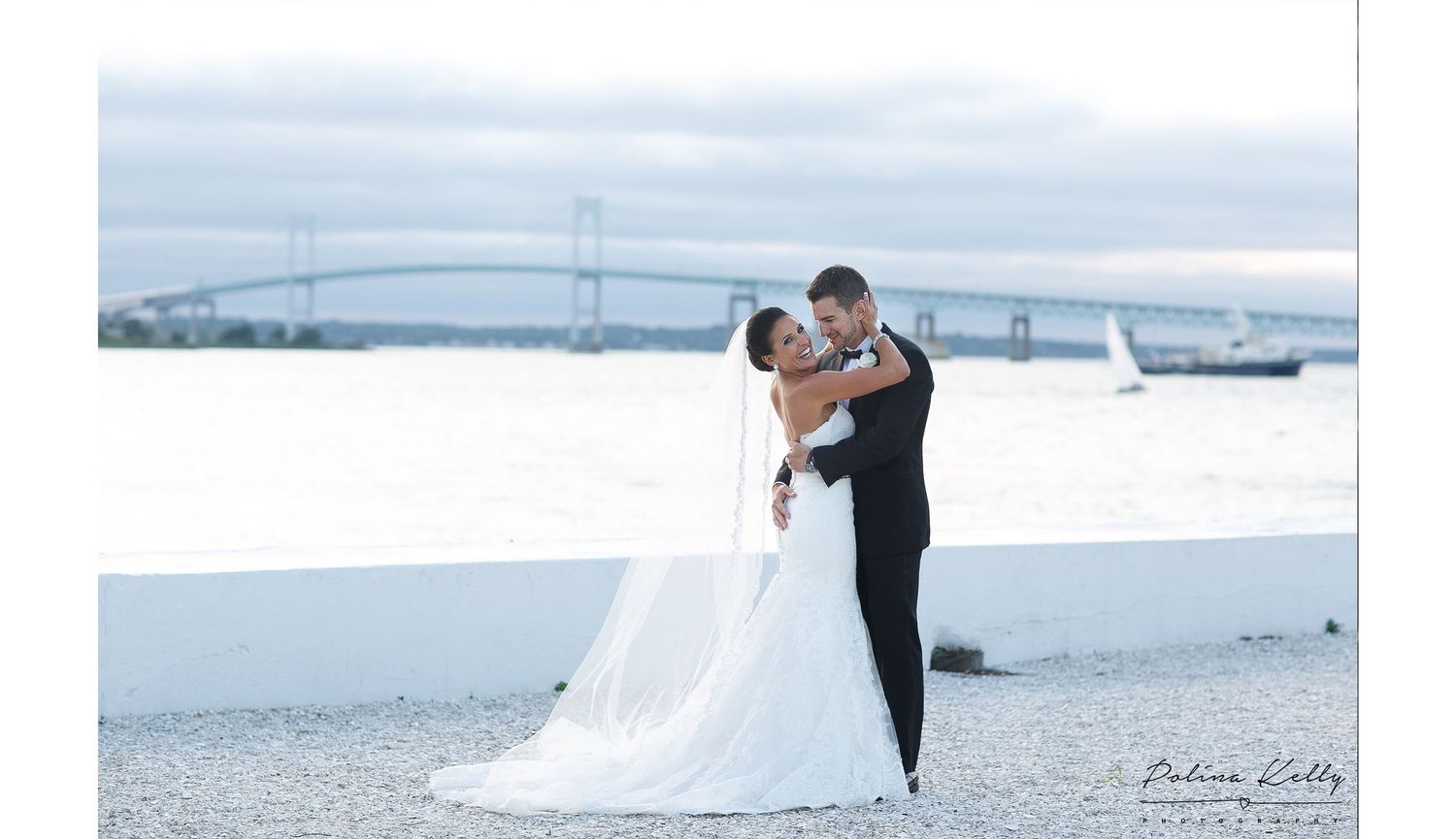 Romantic waterfront wedding portrait with a scenic bridge view. Serving Providence and Newport, RI with expert wedding and family photograph