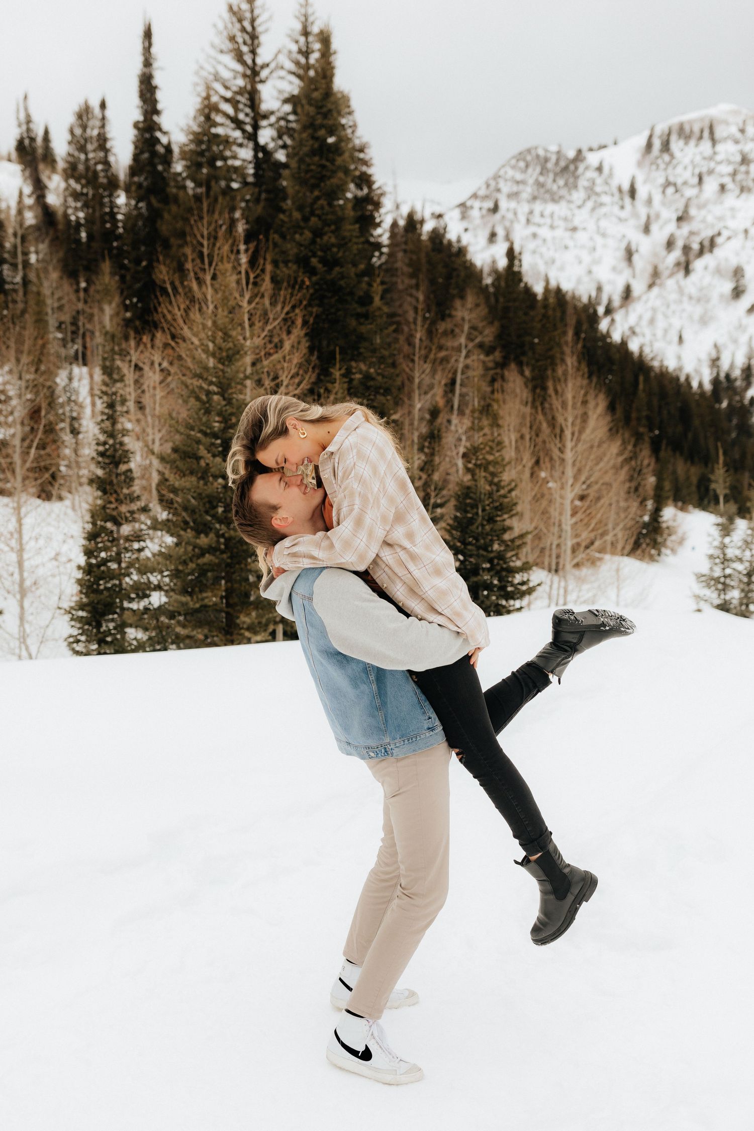 Man lifting woman in the air in the snowy Utah mountains