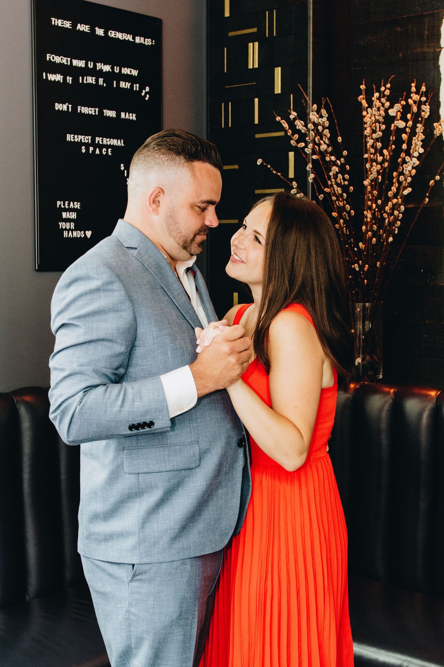 A couple in formal attire shares an intimate moment in a modern restaurant setting.